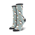 A pair of women's crew socks in light blue with a repeating pattern of illustrated puffins. The socks have dark gray cuffs.
