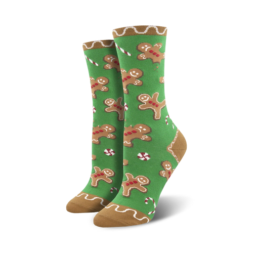 Pair of crew socks with a festive design. Green background with gingerbread men and candy canes. Tan cuff.