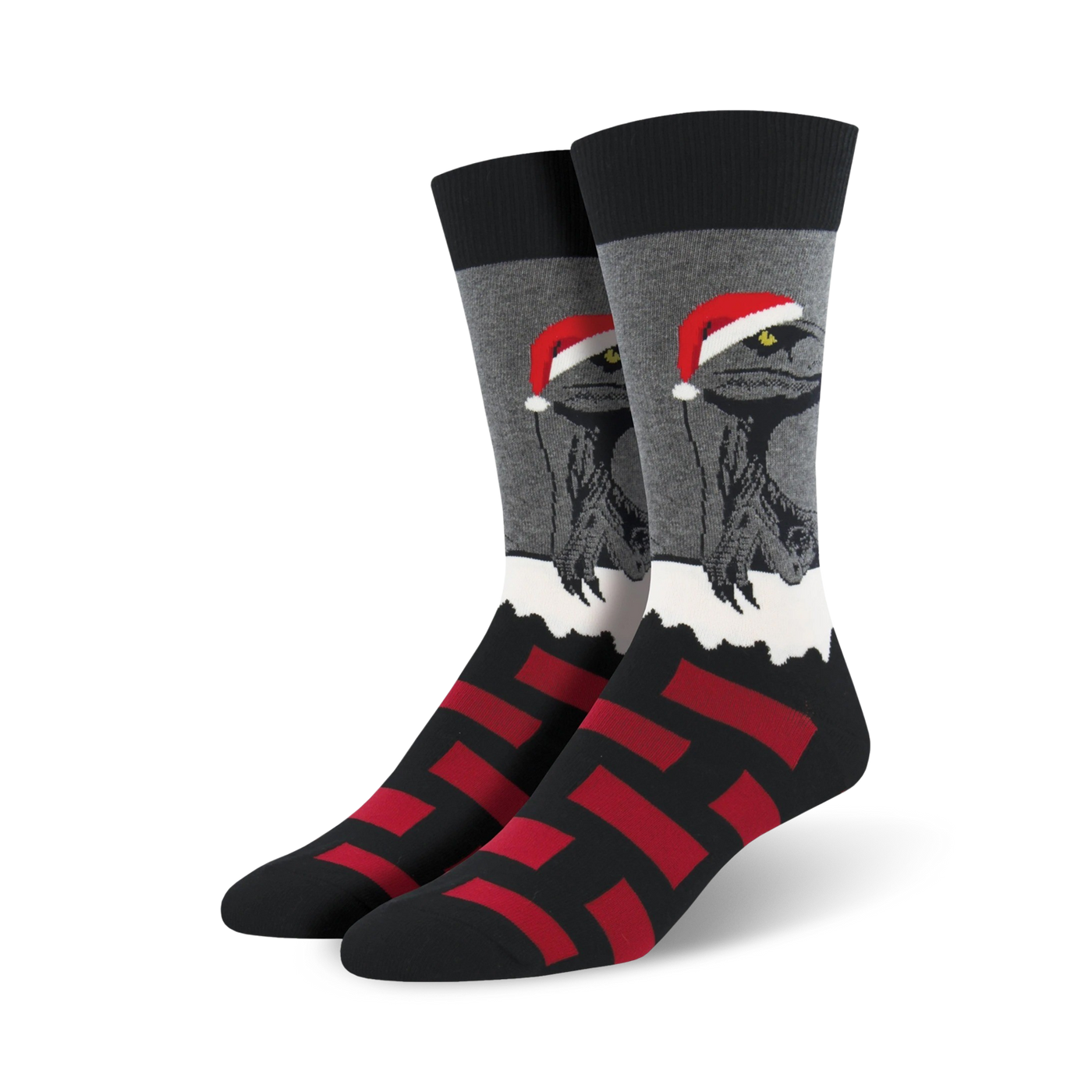 A pair of black, gray, and red crew socks. The main design is a velociraptor wearing a Santa hat, set against a snowy background. Red block pattern at the bottom.