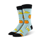 Pair of light blue crew socks with a whimsical pattern of yellow bananas and orange peaches.
