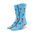 Pair of crew socks in light blue with a repeating pattern of cartoon surfers on red surfboards and blue sharks. 