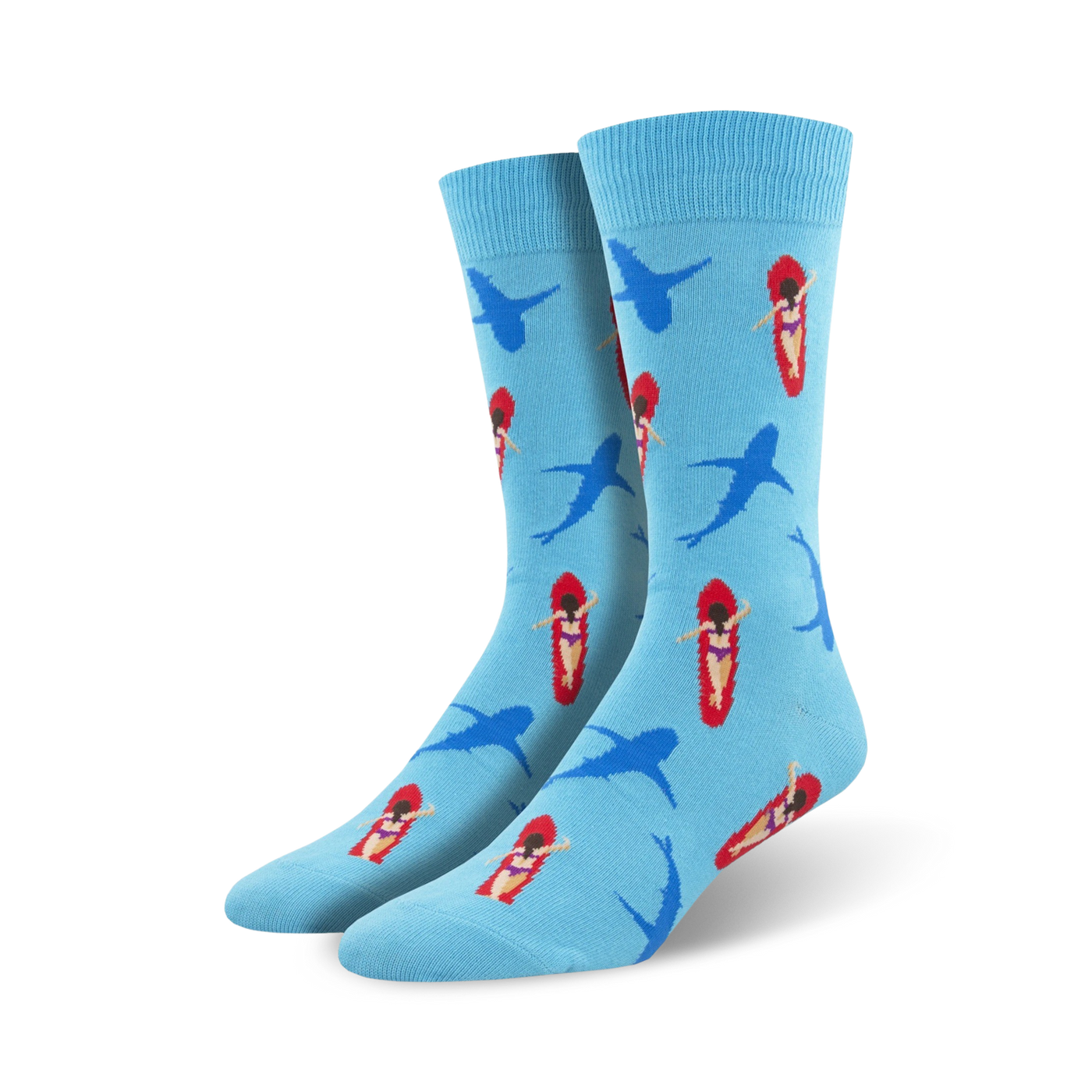Pair of crew socks in light blue with a repeating pattern of cartoon surfers on red surfboards and blue sharks. 