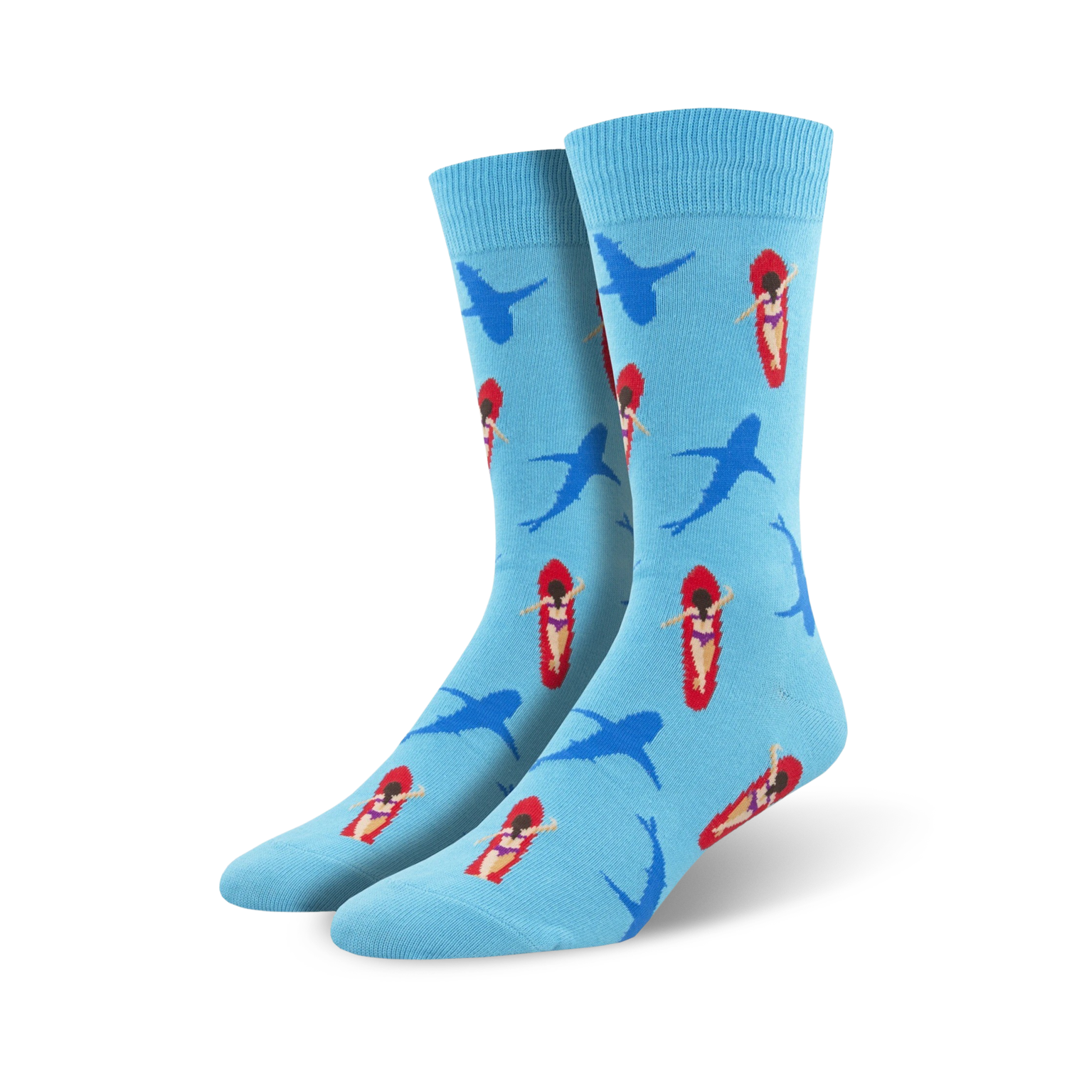 Pair of crew socks in light blue with a repeating pattern of cartoon surfers on red surfboards and blue sharks. 