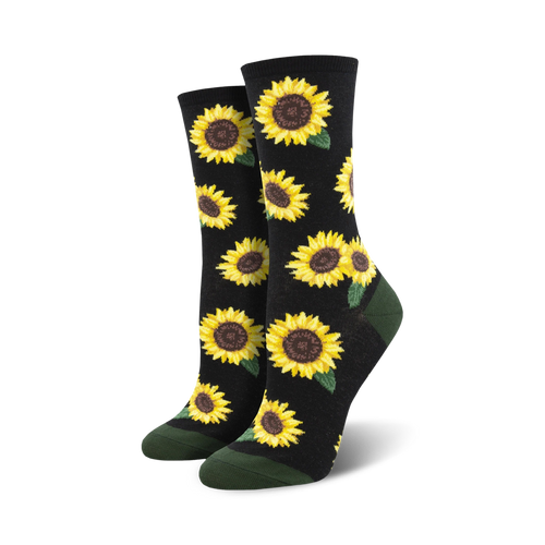 A pair of crew socks with a sunflower pattern. The socks are black with yellow sunflowers and green leaves, and have dark green cuffs.