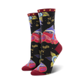 A pair of women's crew socks in black with a colorful design. The main pattern features stylized cat faces in shades of red, purple, and gold, along with smaller floral and geometric details.