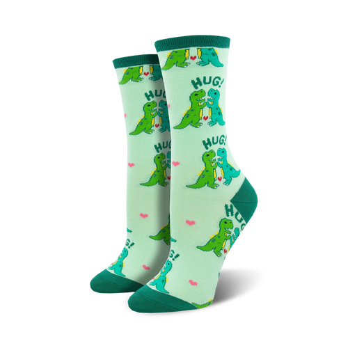 Pair of women's crew socks, light green with teal dinosaurs hugging, and pink hearts. Text says 'HUG!'