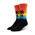 Pair of crew socks with a sunset, palm trees, and ocean wave design.  The socks are mainly black with orange, yellow, and teal accents.