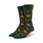 Pair of crew socks in dark green featuring a repeating pattern of grinning jack-o'-lanterns and black cats with bright green eyes.
