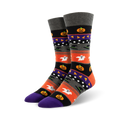 A pair of crew socks with a Halloween theme. The design includes orange, purple, black, and grey stripes with pumpkins, ghosts, and witches' hats.