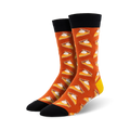 A pair of crew socks in burnt orange with a repeating pattern of pumpkin pie slices. The socks have black cuffs and yellow heels.
