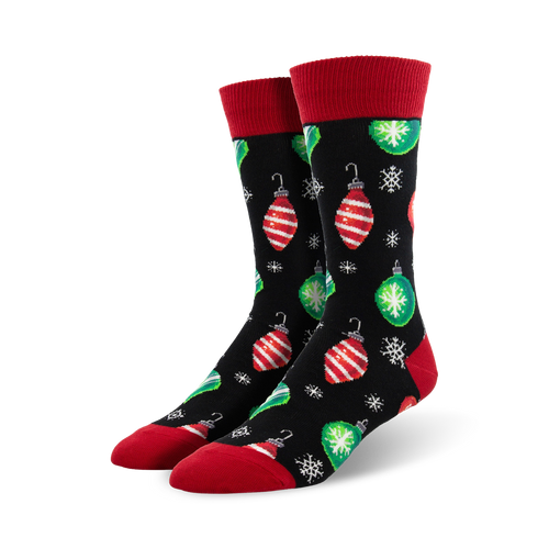 Pair of crew socks with a black background, red and green Christmas ornaments, and snowflakes. Red cuffs.