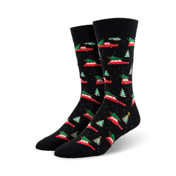 A pair of black crew socks with a pattern of red cars carrying Christmas trees and small green trees. Festive and fun!