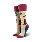 A pair of beige crew socks with maroon cuffs. The socks feature a desert landscape design with cowboy boots, cacti, and birds.