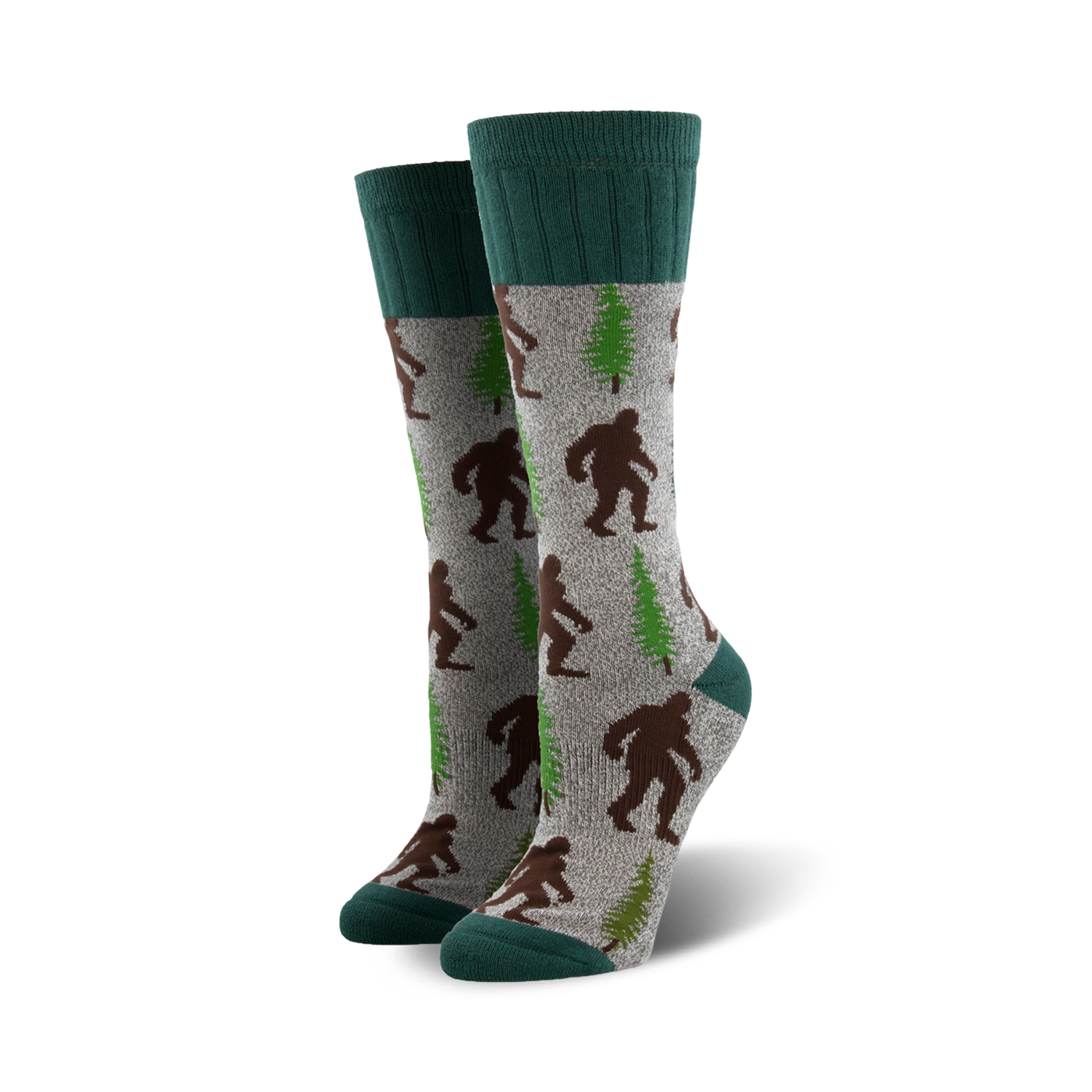 A pair of grey crew socks with brown Bigfoot and green trees. The socks have teal cuffs.