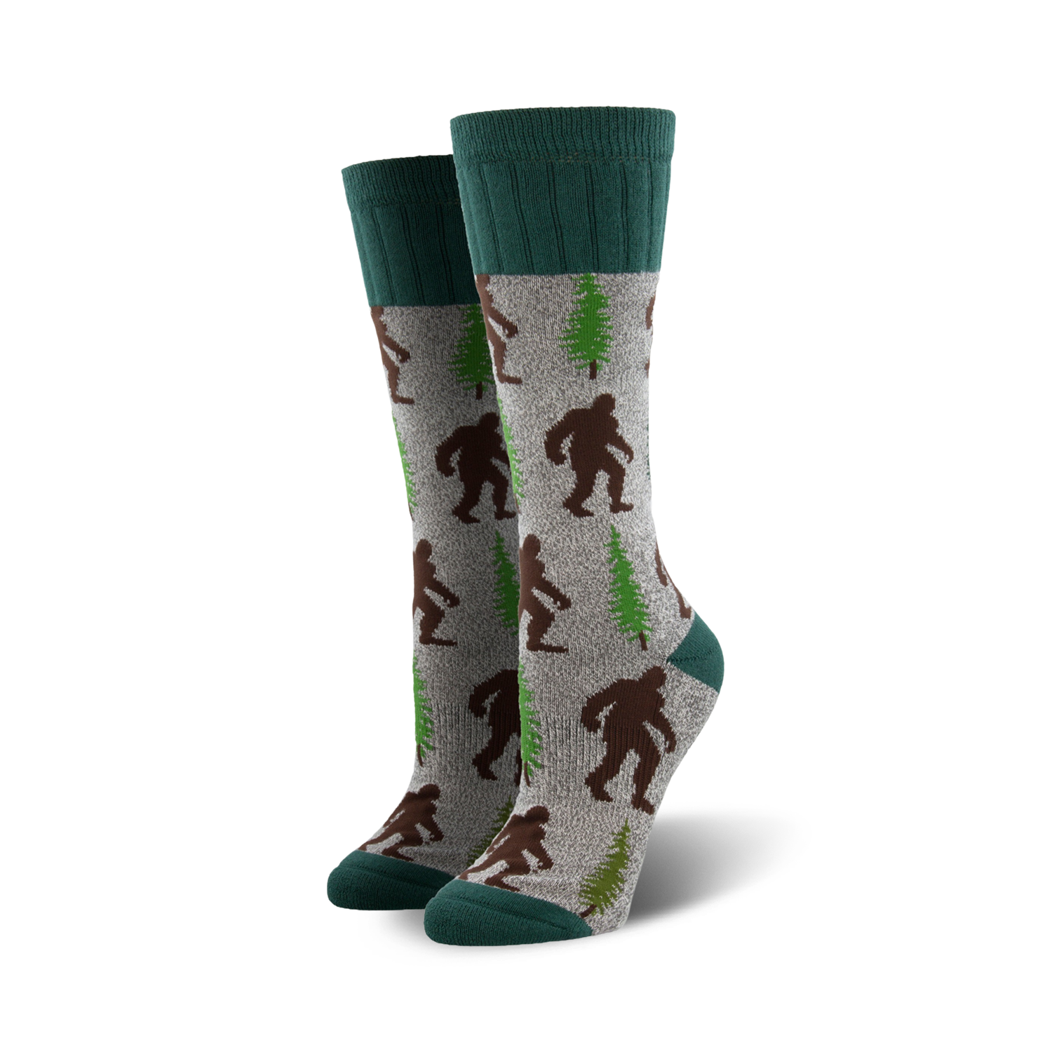 A pair of grey crew socks with brown Bigfoot and green trees. The socks have teal cuffs.