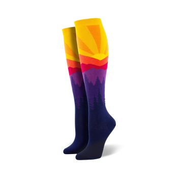 women's knee-high mountain sun socks with purple, blue, orange, and yellow pattern of pine trees and a setting sun.  
