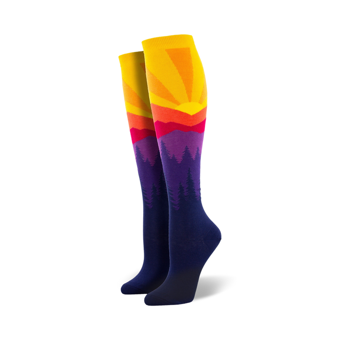 women's knee-high mountain sun socks with purple, blue, orange, and yellow pattern of pine trees and a setting sun.   }}