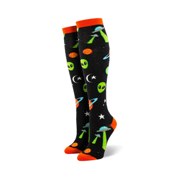 black womens knee high novelty socks feature green aliens, orange crescent moons, stars, planets, and flying saucers.    