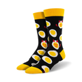 A pair of black crew socks with a fun pattern of yellow deviled eggs. The eggs have small red devil horns and mischievous smiles.