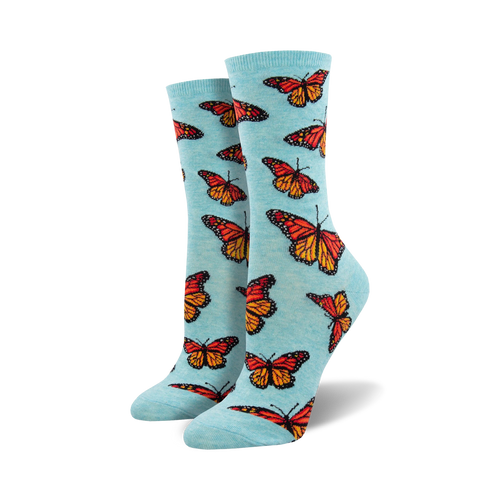 Lifestyle shot: A woman's foot wearing a light blue Social Butterfly sock. The sock showcases the bright orange and red monarch butterfly design.