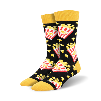 black popcorn socks with "pop!" written on red and white popcorn boxes, loose popcorn scattered about, yellow top. crew length, men's sizing.   