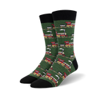 Pair of crew socks with a repeating pattern of red and gray vintage train designs on a green background. Black cuff.