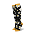 Pair of black knee-high socks with white smiling daisy pattern and mustard yellow cuffs.