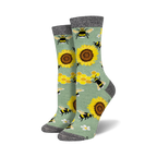 Pair of crew socks with bees, sunflowers, and honeycomb pattern on a sage green background.  Black and grey top cuff.