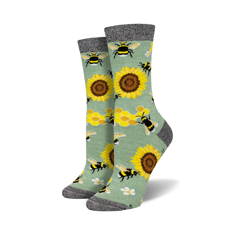 Pair of crew socks with bees, sunflowers, and honeycomb pattern on a sage green background.  Black and grey top cuff.