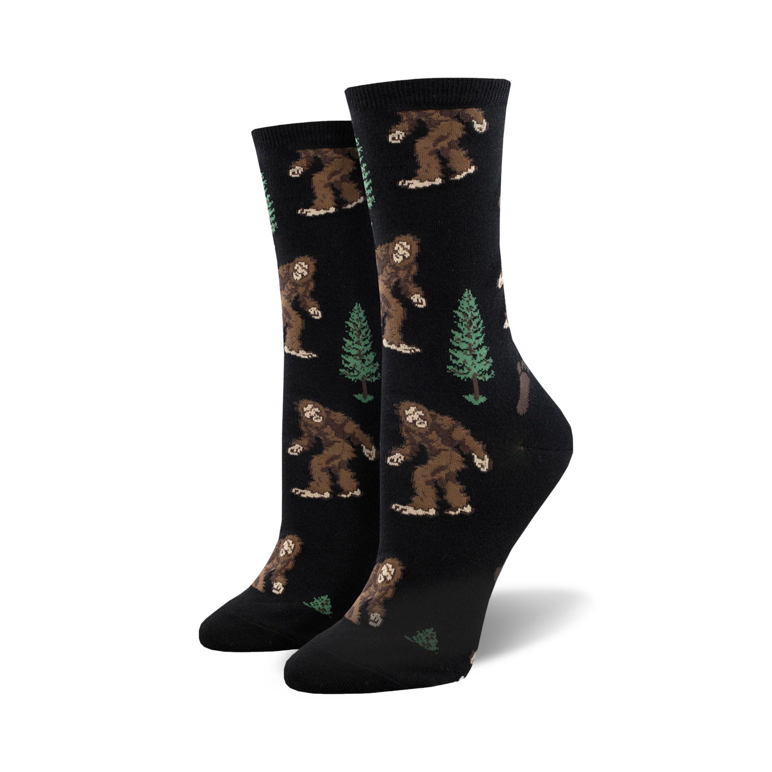 Pair of women's crew socks. Black background with repeating pattern of brown Bigfoot figures and green evergreen trees.