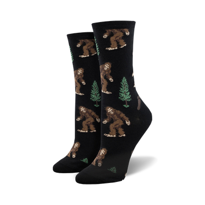 crew length socks for women with pattern of bigfoot creatures walking amidst green pine trees  