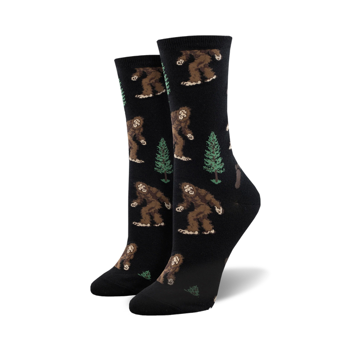 crew length socks for women with pattern of bigfoot creatures walking amidst green pine trees   }}