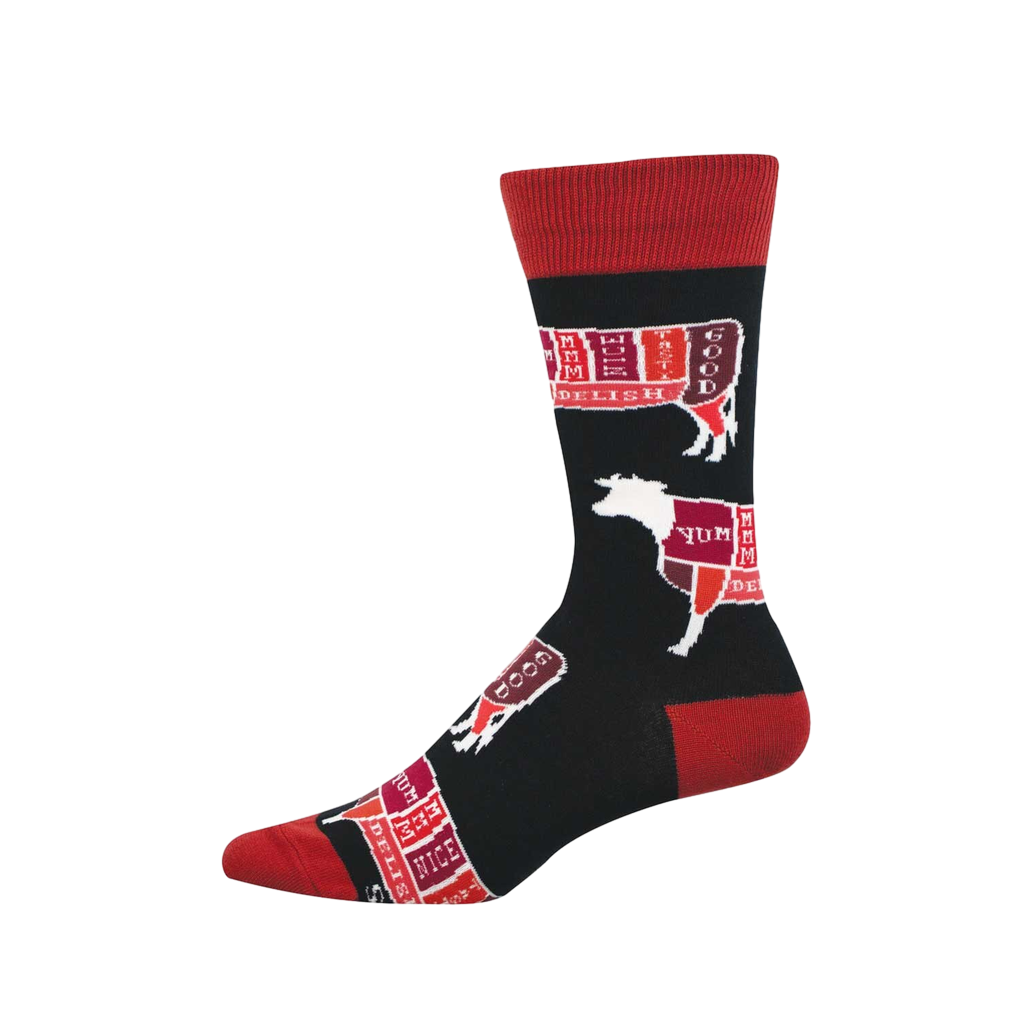 Black crew socks with red cuffs, heel, and toe. Features white outlines of cattle divided into colorful butcher cuts labeled 'YUM' and 'DELISH.'
