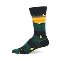 Single crew sock showing dark green mountains, snow caps, orange and yellow striped sky, moon, stars, pine trees, and campfires.
