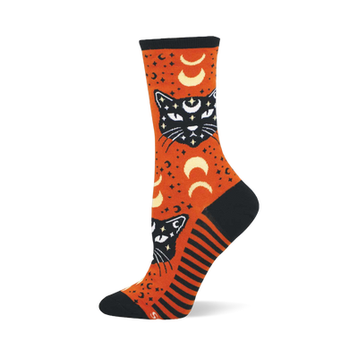 Orange crew sock with black mystic cats, white eyes, crescent moons, and stars. Features black toe, heel, cuff, and striped side panel.