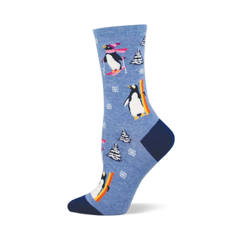 Light blue crew sock with skiing and snowboarding penguins, white snowflakes, and snow-covered pine trees. Dark blue heel and toe.