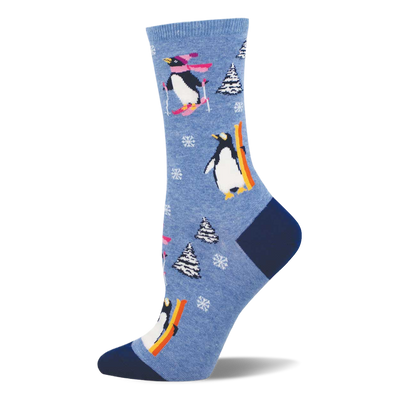 Light blue crew sock with skiing and snowboarding penguins, white snowflakes, and snow-covered pine trees. Dark blue heel and toe.