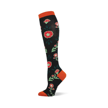 A knee-high black sock with a pattern of red flowers, light green centers, and dark green leaves. Features orange cuff, heel, and toe.