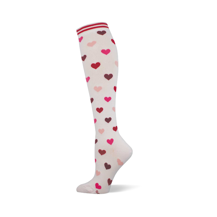 Cream knee-high sock with a scattered pattern of pink, red, and maroon hearts. Features a white and red striped cuff. }}