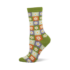 Side view of a crew sock with a checkerboard of light green, orange, and purple squares, each with a white daisy. Dark green cuff, heel, and toe.