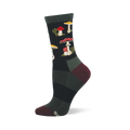 Single dark crew sock with a repeating pattern of red and white spotted mushrooms, yellow-capped mushrooms, and green foliage. Dark green cuff, burgundy heel and toe.