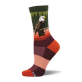 Crew sock with a bald eagle perched on a stump. Dark green cuff, green tree pattern, orange and brown stripes, color block foot.