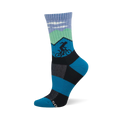 Blue and green crew sock with mountain scene, white clouds, and a dark silhouette of a cyclist. Blue and black checkerboard foot design.
