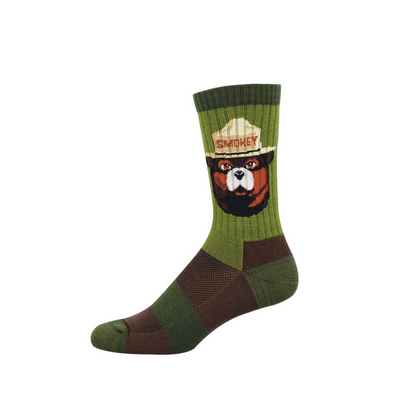 A green crew sock featuring Smokey Bear's head in a tan ranger hat with "SMOKEY" text. The sock has green and brown textured patterns.