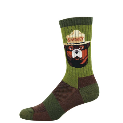 A green crew sock featuring Smokey Bear's head in a tan ranger hat with "SMOKEY" text. The sock has green and brown textured patterns.