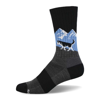 A single black crew sock featuring a black and white husky running over a grey hill with blue sky and white mountains.