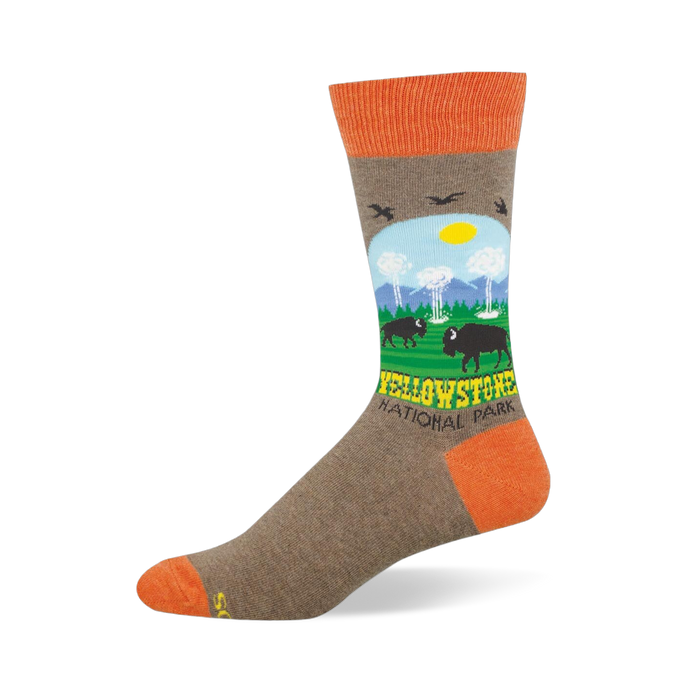 Heather brown crew sock with orange accents featuring a Yellowstone scene with bison, geysers, mountains, and trees. }}
