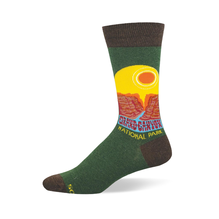 Green crew sock with brown accents featuring a retro Grand Canyon National Park graphic, yellow sun, and red cliffs. }}