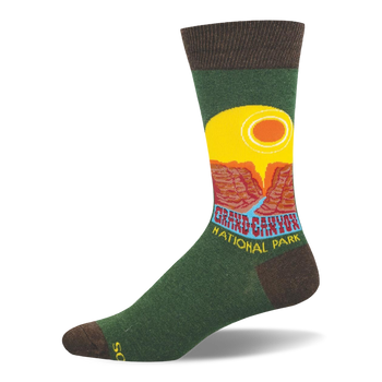 Green crew sock with brown accents featuring a retro Grand Canyon National Park graphic, yellow sun, and red cliffs.