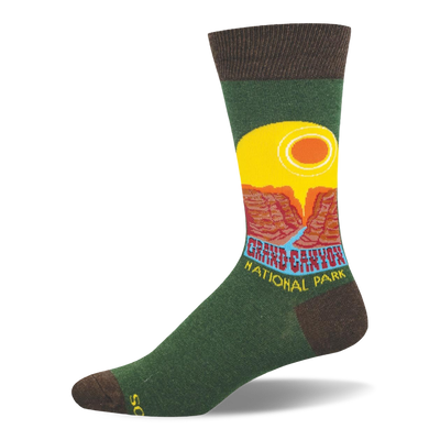 Green crew sock with brown accents featuring a retro Grand Canyon National Park graphic, yellow sun, and red cliffs.